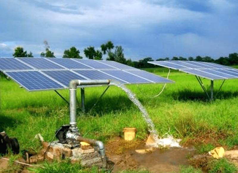 Solar panels powering a water pump in a green field